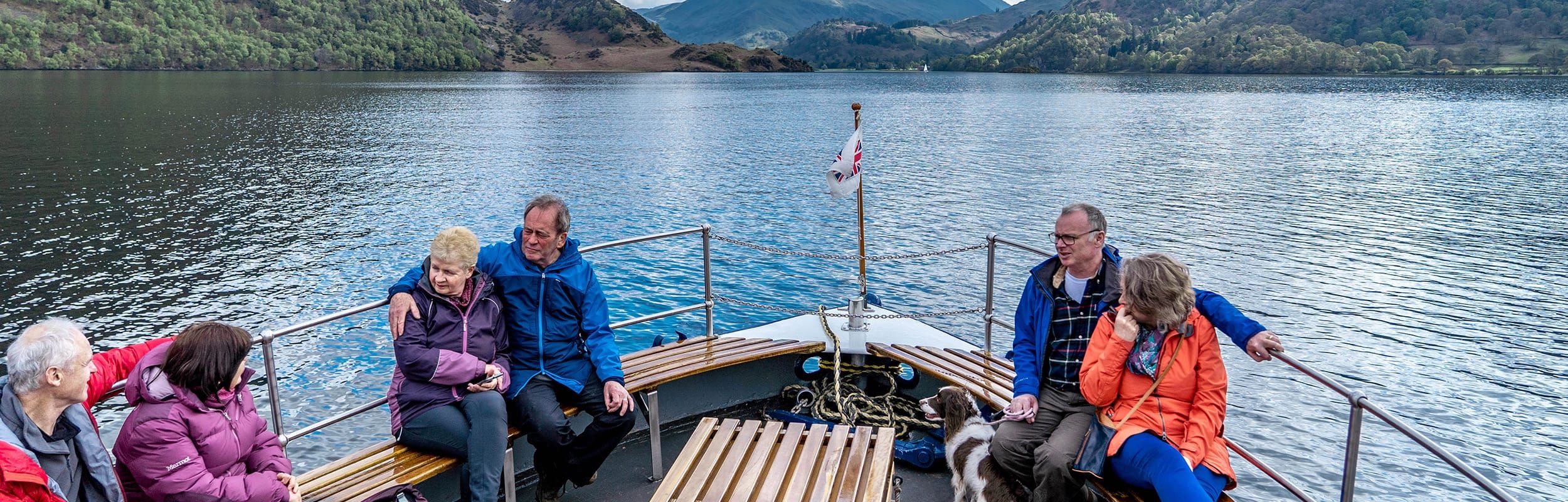 Group sat at the front of boat sailing along Ullswater